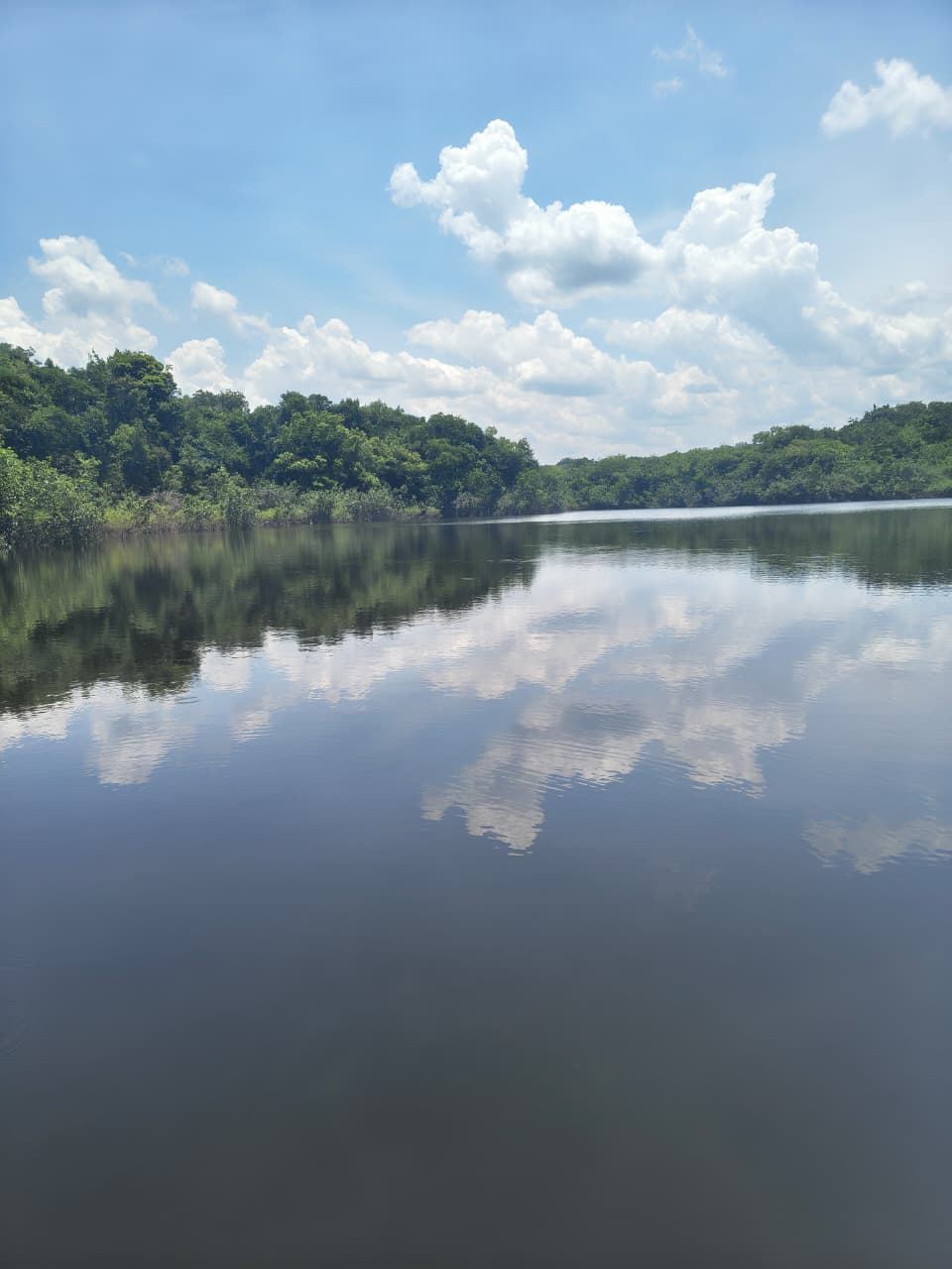 Lago de águas escuras refletindo as nuvens